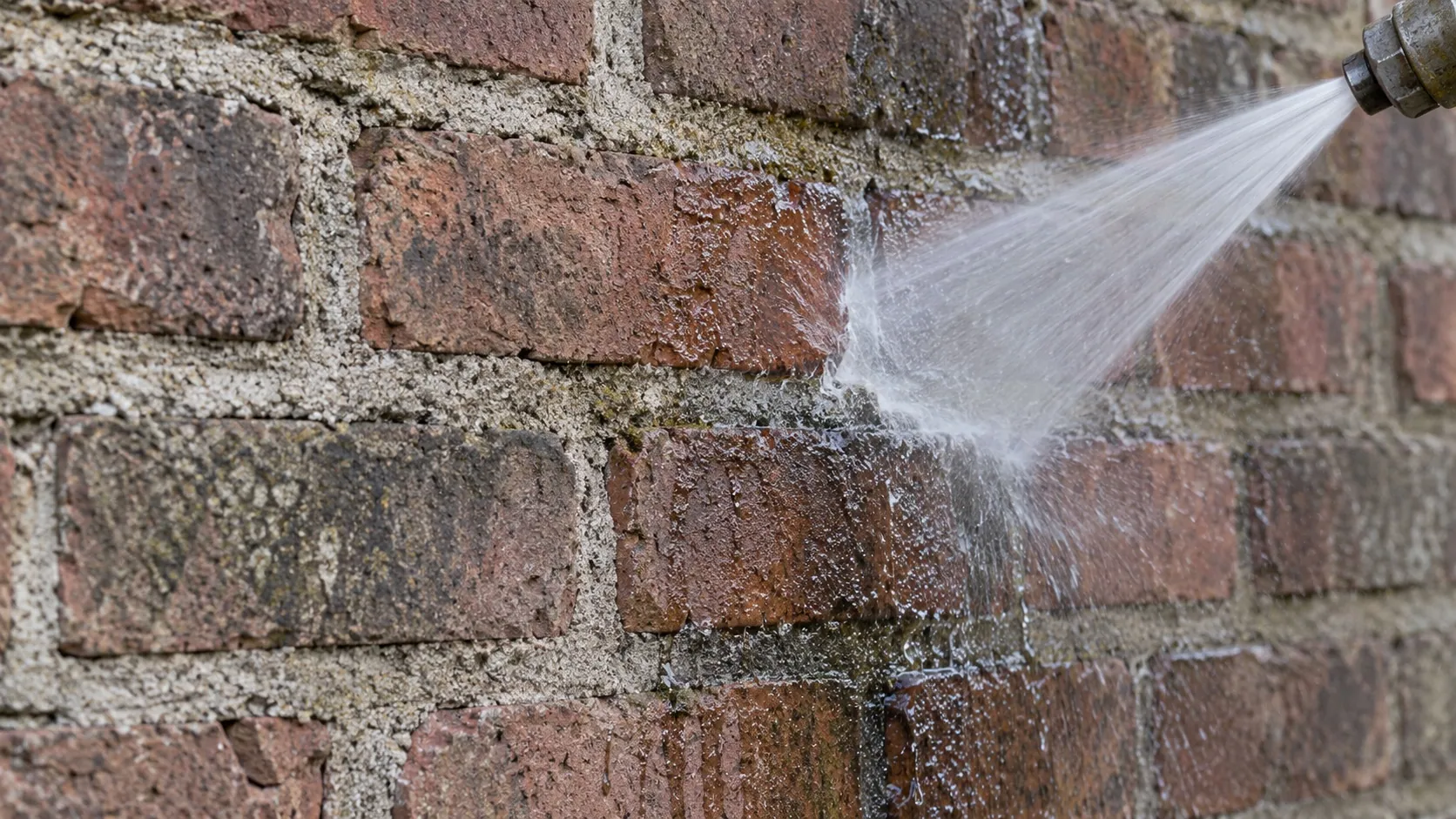 A fan of water meeting weathered brick and mortar in close-up